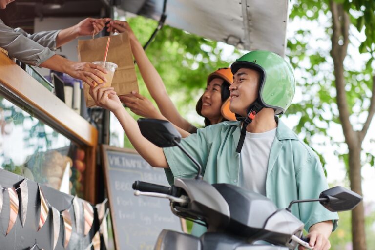 Food delivery riders picking up an order at a Thai street food truck