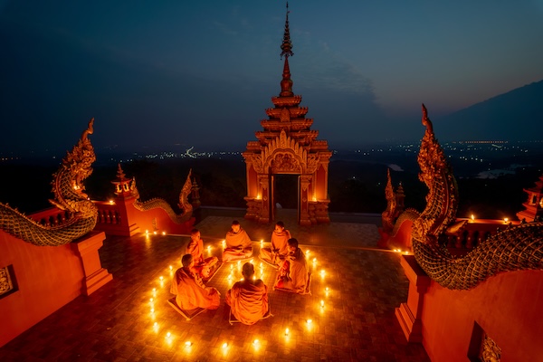 Buddhist monks meditating in a circle of candlelight during Visakha Bucha in Thailand