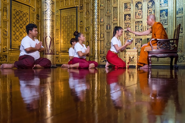 Young Thai people offering gifts to a Buddhist monk during Visakha Bucha rituals