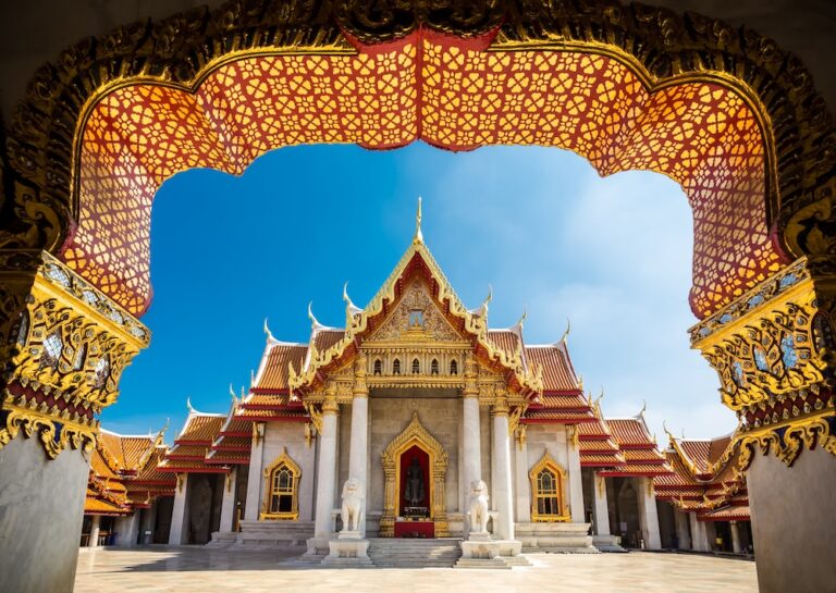 A Thai Buddhist temple viewed through a richly decorated archway, symbolizing Thai religious tradition