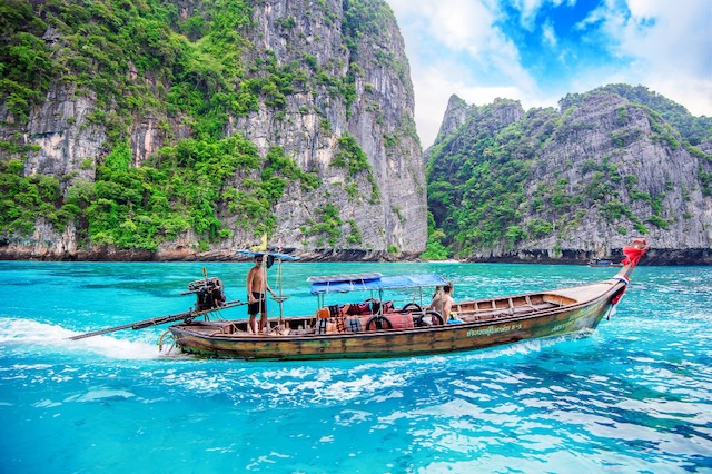 Traditional Thai longtail boat on turquoise waters near the cliffs of Phi Phi Islands