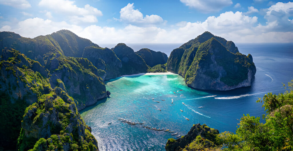 Aerial view of Maya Bay in Krabi, Thailand, with turquoise waters, white sand beach, and dramatic limestone cliffs.
