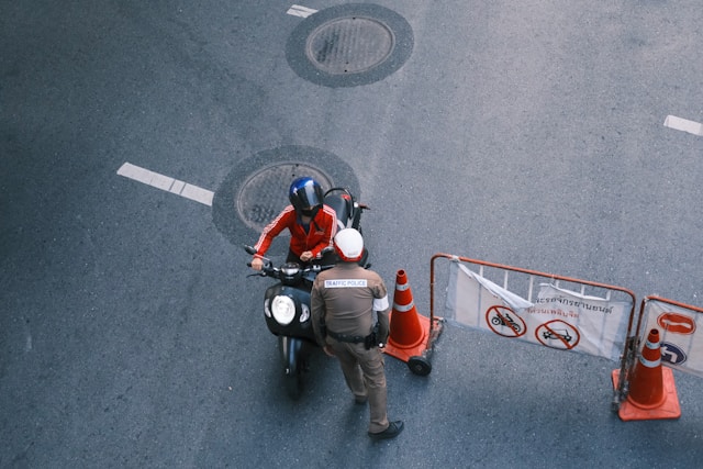 Police officer inspecting a motorbike rider at a traffic checkpoint in Thailand