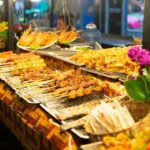 Various Thai grilled skewers displayed at a night market food stall