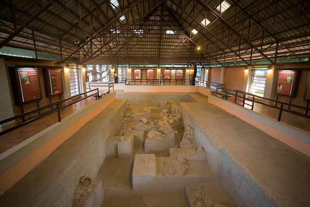 Excavated prehistoric burial site inside the Ban Chiang Archaeological Museum, with pottery and ancient artifacts on display