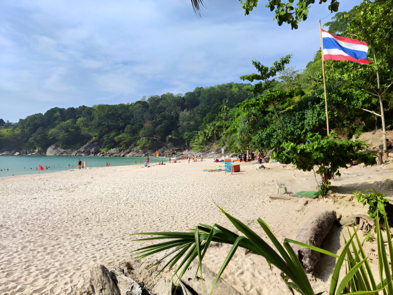 Thailand tourism 2025: A beautiful sandy beach with turquoise water, lush greenery, and the Thai flag.