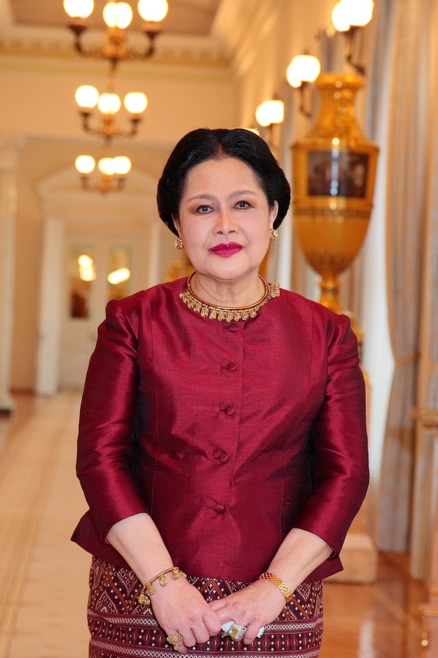 Official portrait of Queen Mother Sirikit wearing a traditional red Thai silk outfit, illustrating her role as a cultural icon.