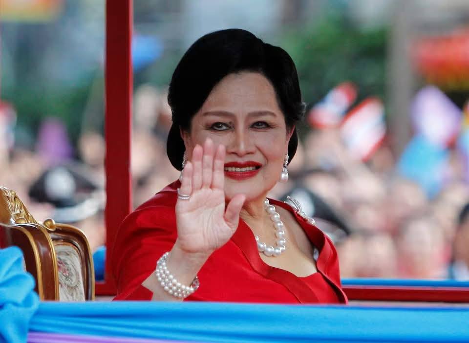 Official portrait of Queen Mother Sirikit of Thailand, smiling and waving to the public during a royal ceremony.