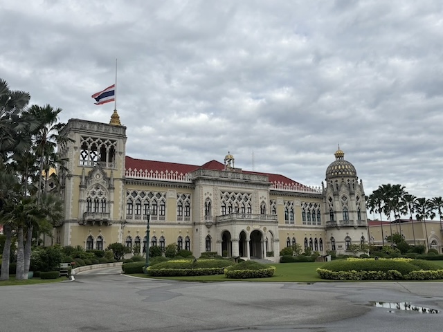 The Thai flag at half-mast in front of the Government House in Bangkok, marking the national mourning period after Queen Mother Sirikit's death.
