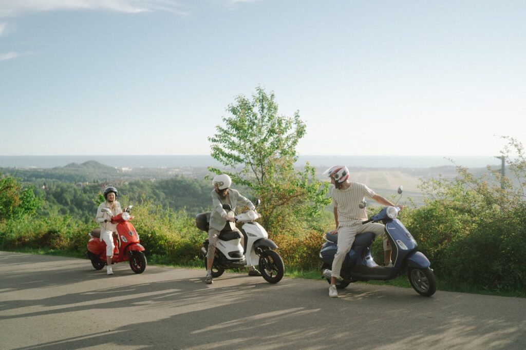 Three tourists wearing helmets on scooters overlooking a scenic landscape in Thailand