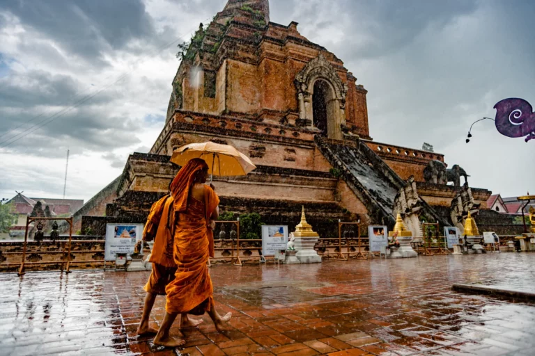 The large brick chedi at Wat Chedi Luang in Chiang Mai in the rain, with a monk in the foreground.