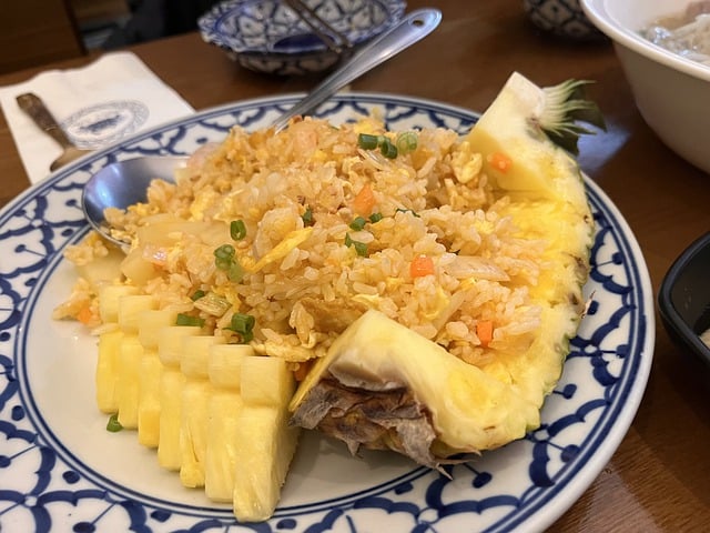 Riz frit à l'ananas servi dans une demi-coque d'ananas avec des morceaux d'ananas frais.