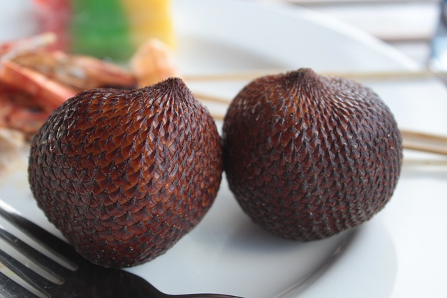 Deux salak ou fruits serpent sur une assiette blanche avec des couverts à côté.