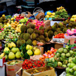 Étals colorés de fruits exotiques sur un marché local en Thaïlande, avec durians, mangues, pitayas et ramboutans