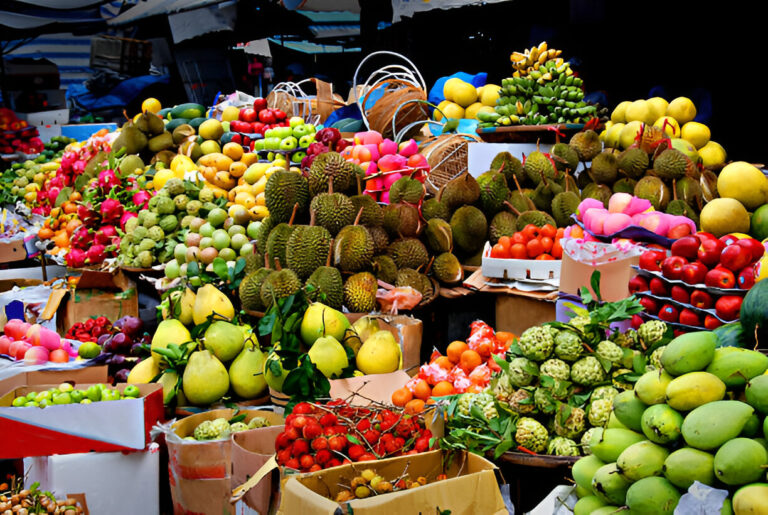 Étals colorés de fruits exotiques sur un marché local en Thaïlande, avec durians, mangues, pitayas et ramboutans
