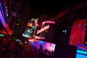 Soi Cowboy la nuit à Bangkok avec des enseignes au néon pour des bars de ladyboys