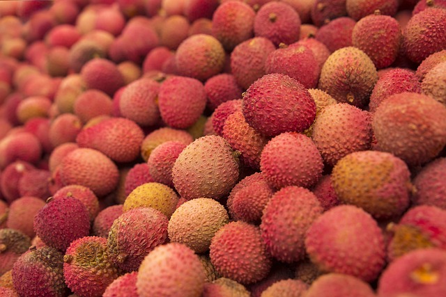 Abondance de litchis mûrs avec des textures variées allant du rose au rouge.