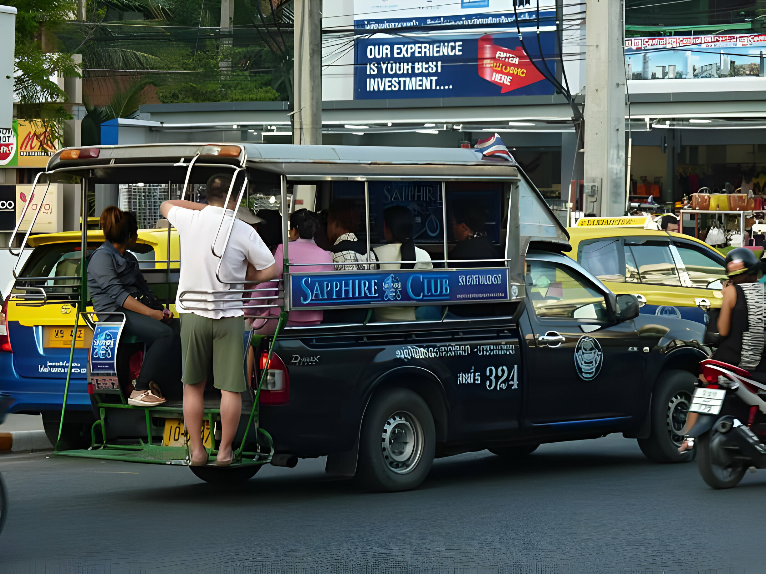 Passagers montant dans un songteo bleu sur une route animée de la ville.
