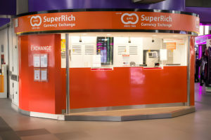 Bureau de change de devises SuperRich de couleur orange dans un espace commercial.