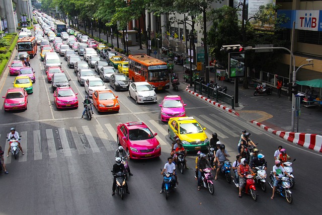 Vue aérienne d'une rue animée avec un mélange de voitures colorées et de motos à un carrefour.