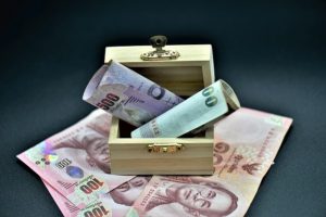 Billets de baht thaïlandais dans une petite boîte en bois ouverte.