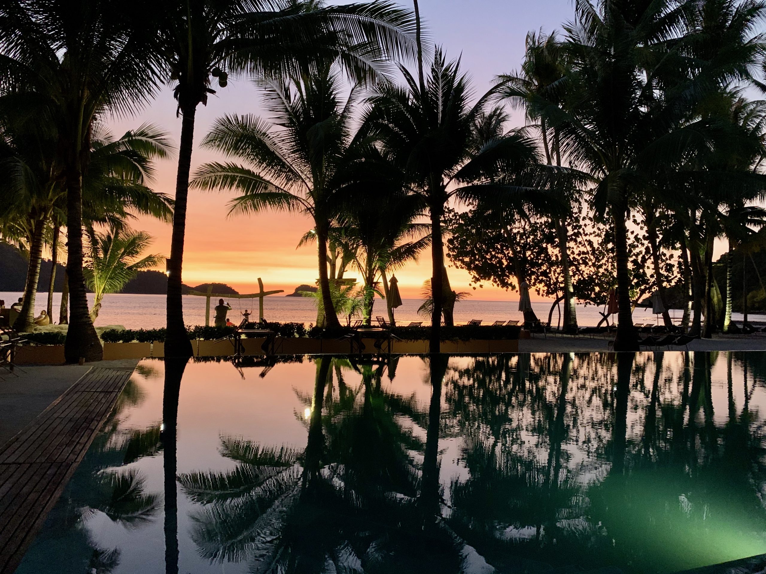 Coucher de soleil à Koh Chang avec piscine et palmiers en silhouette
