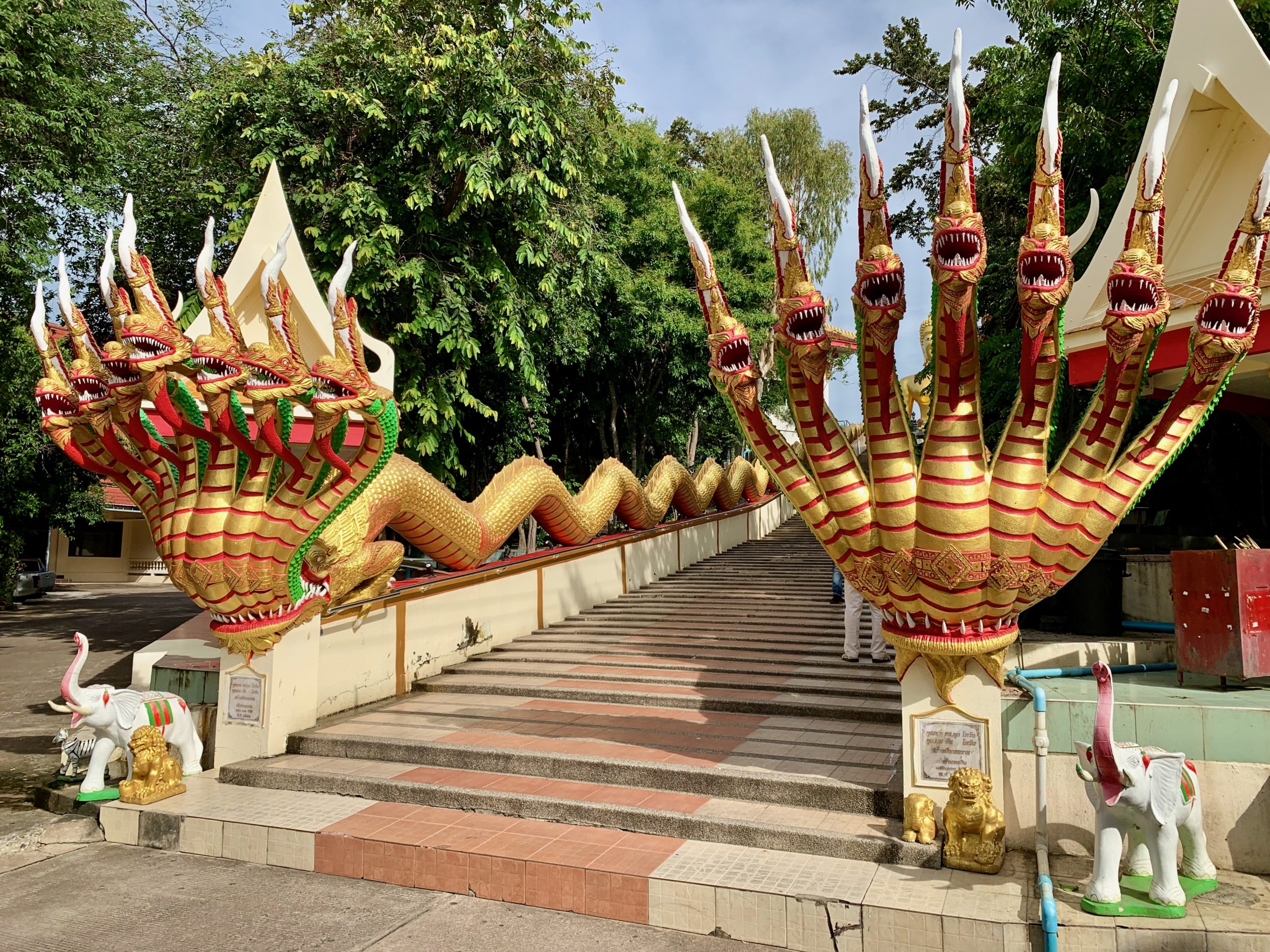Escalier orné de sculptures de dragons en or rouge dominant l'entrée d'un temple à Pattaya