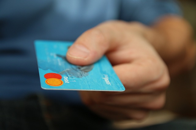 Main tenant une carte de crédit bleue avec logo Mastercard.