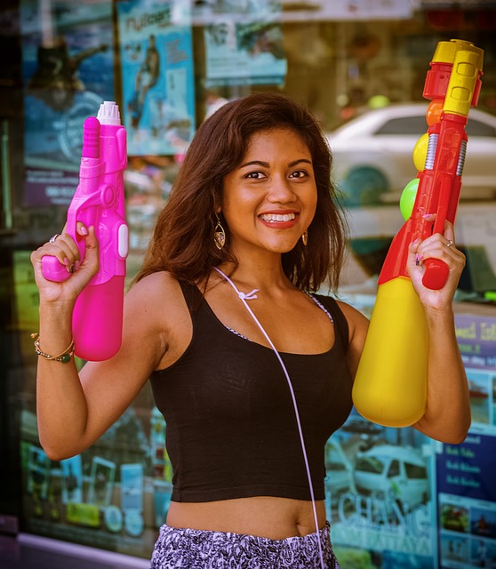 Femme souriante armée de deux pistolets à eau colorés prête pour Songkran