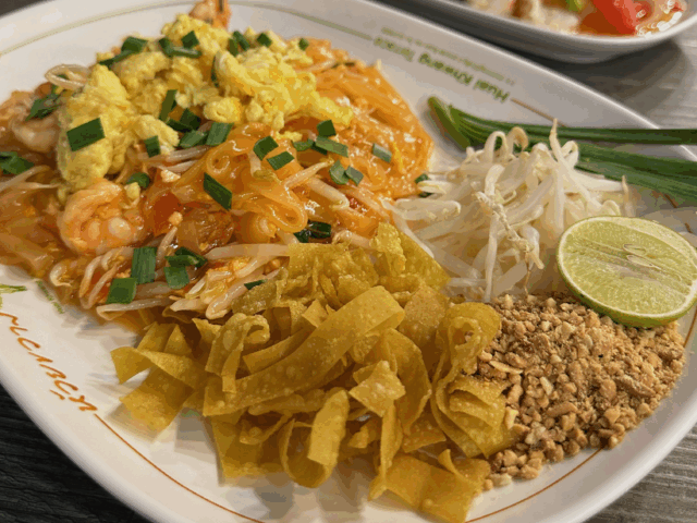 Plat de Pad Thaï garni de crevettes, citron vert et cacahuètes