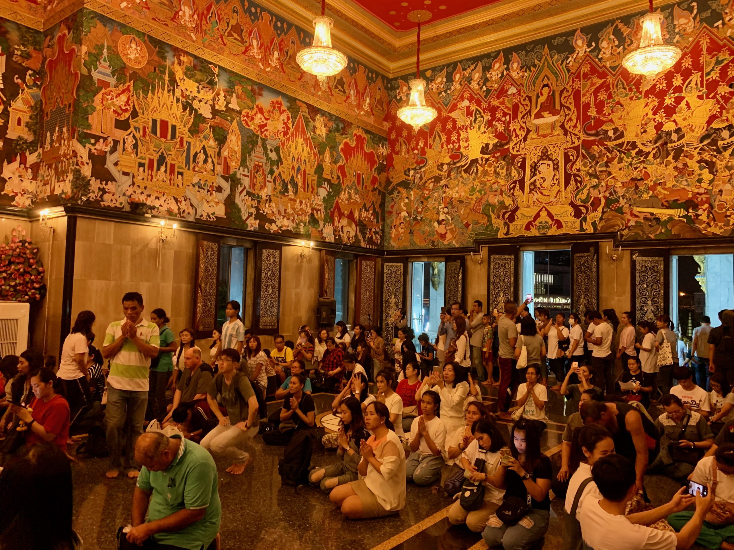 Fidèles rassemblés pour Makha Bucha dans un temple orné de fresques à Bangkok.