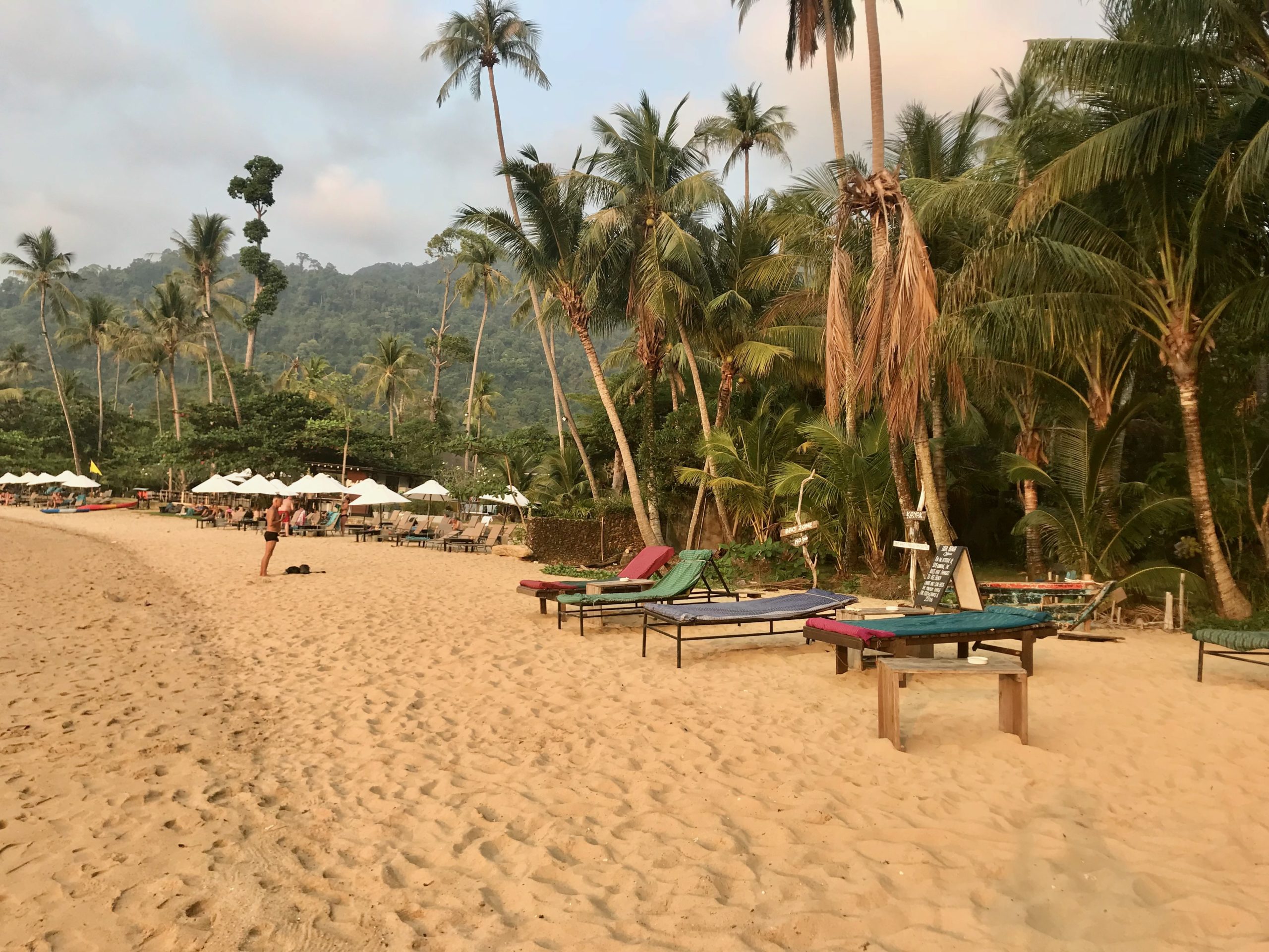 Plage de sable au crépuscule avec palmiers et transats à Koh Chang