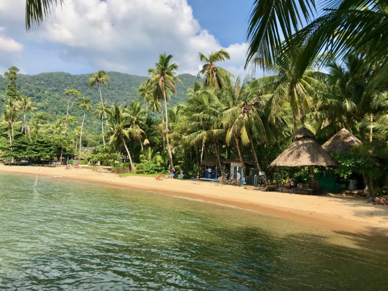 Vue paisible d'une plage de Koh Chang avec des huttes et des palmiers