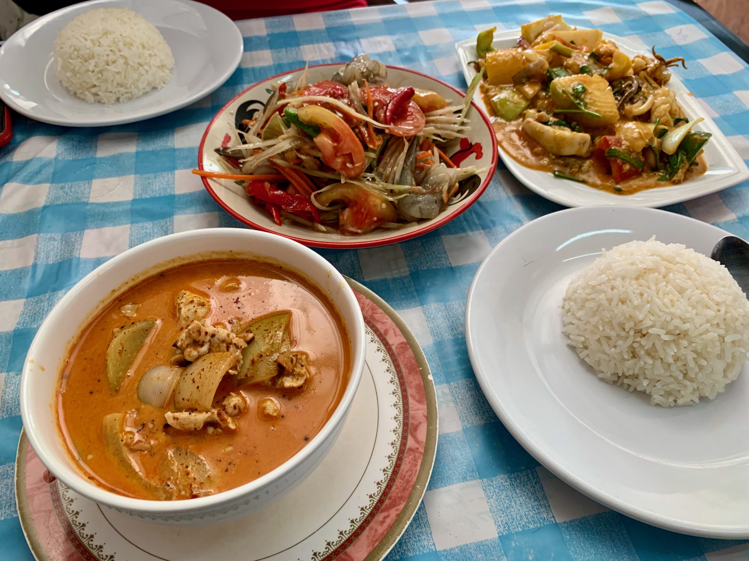 Assortiment de plats thaïlandais avec curry, salade de papaye et riz.