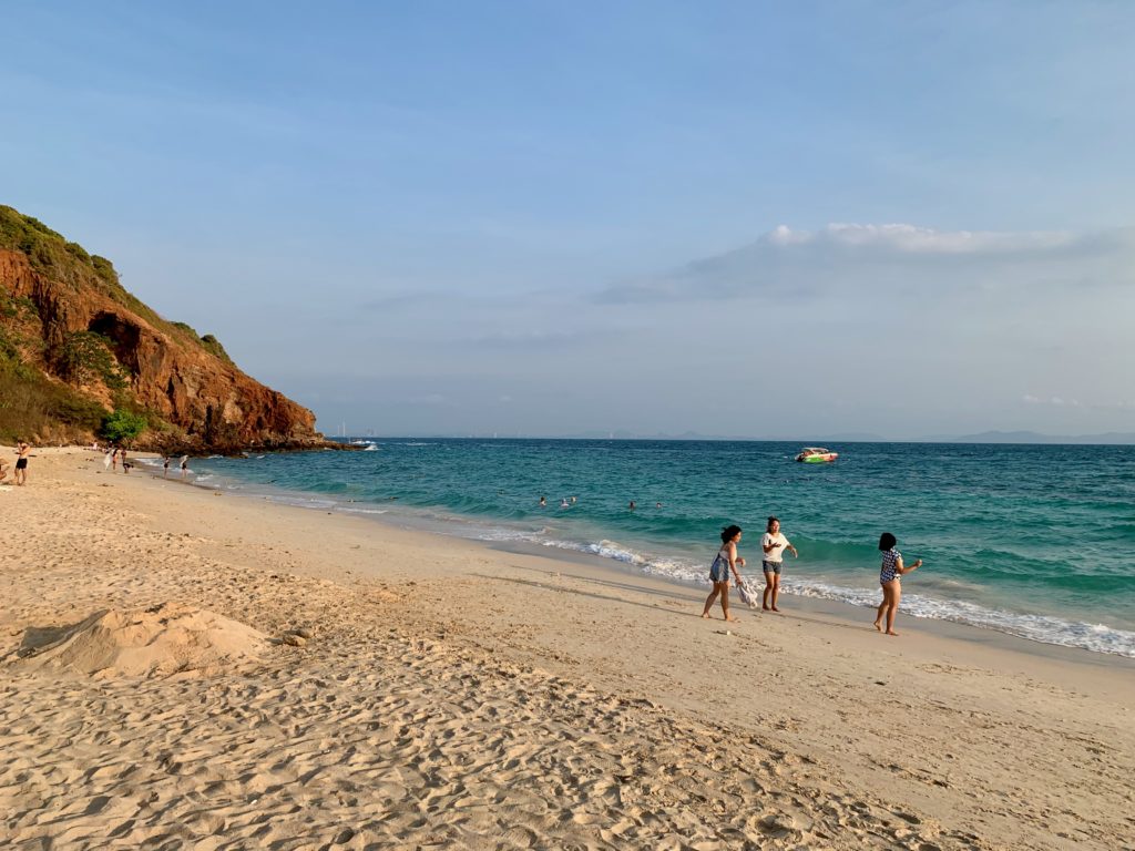 Plage de Nual à Koh Larn avec sable doré, mer calme et collines verdoyantes en arrière-plan