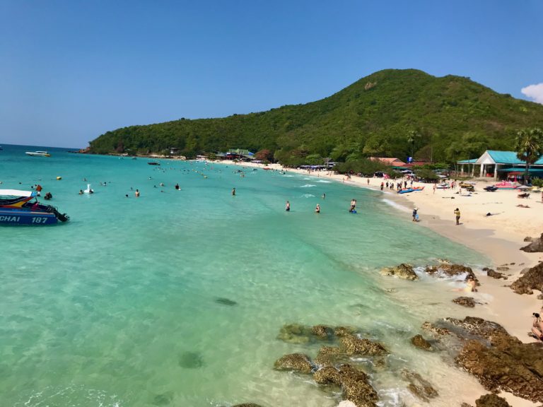 Plage animée à Koh Larn avec eaux turquoise et montagne en arrière-plan