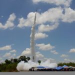 Fusée artisanale s'envolant sous un ciel bleu pendant le festival Bun Bang Fai en Thaïlande
