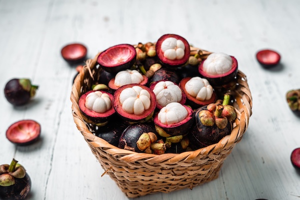 Fresh mangosteens in a wicker basket at a Thai market
