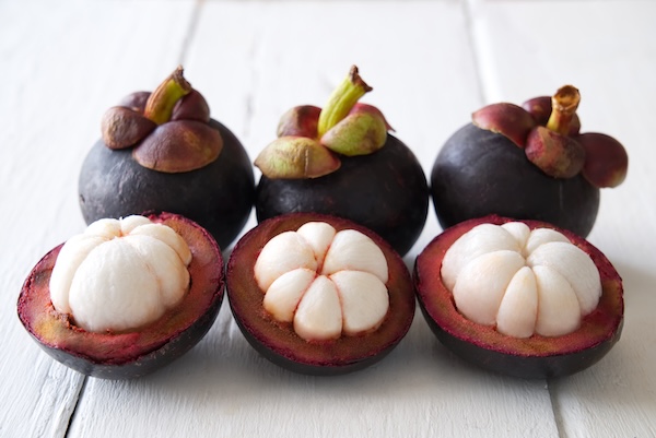 Juicy white fruit segments inside thick purple shells