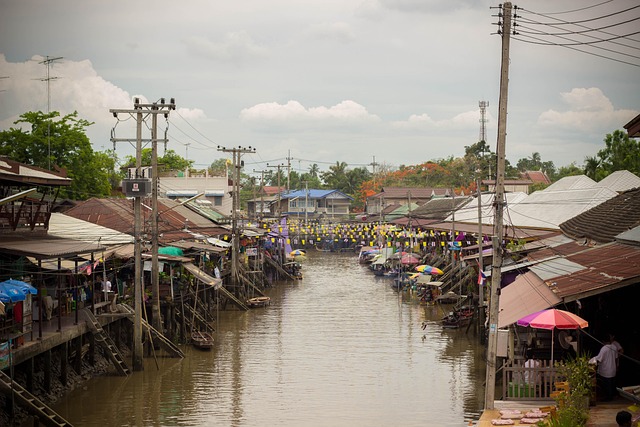 Maisons sur pilotis et étals au bord d’un canal dans un marché flottant thaïlandais