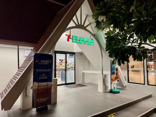 Façade nocturne d'un magasin 7-Eleven en Thaïlande, caractérisée par un toit d'architecture thaïe et une enseigne lumineuse.
