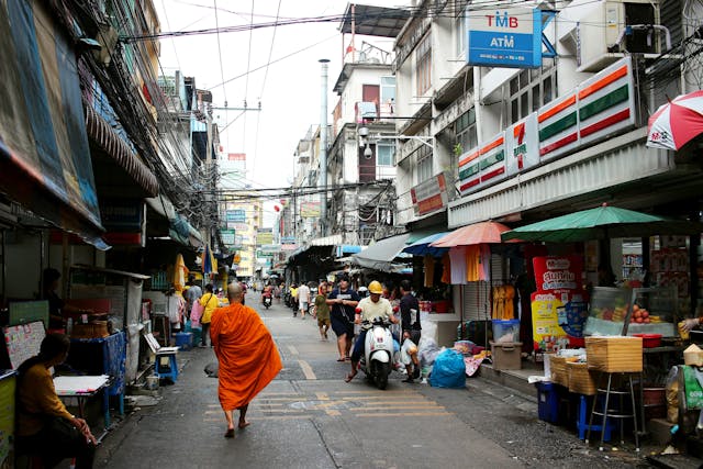 Un moine passe devant un magasin 7-Eleven en Thaïlande dans une ruelle locale animée