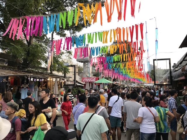 Foule animée sous des rubans colorés dans une allée du marché de Chatuchak à Bangkok