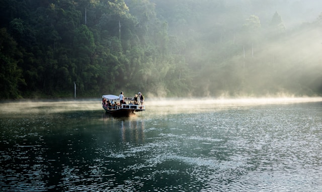 Touristes à bord d’un longtail boat sur le lac Cheow Lan au lever du jour, au cœur de la forêt de Khao Sok
