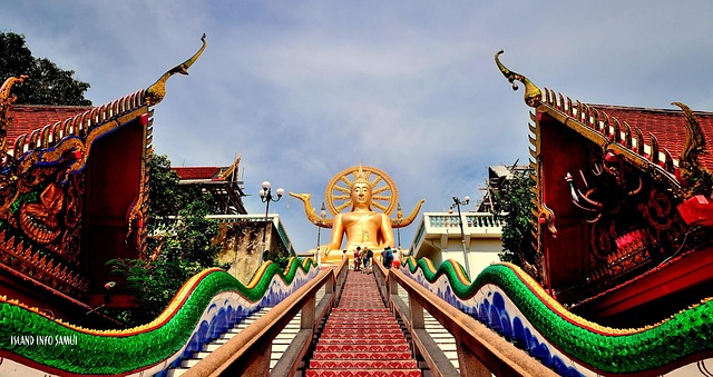 Statue dorée du Big Buddha à Koh Samui vue depuis l’escalier orné de nagas colorés, sous un ciel clair