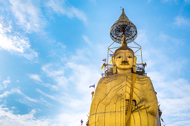 Bouddha géant doré du Wat Intharawihan à Bangkok, sur fond de ciel bleu