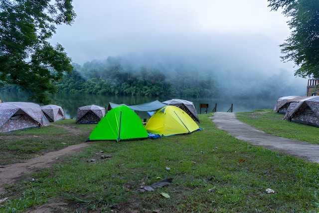 Tentes de camping installées au bord de la rivière dans le parc national d’Erawan, Kanchanaburi, Thaïlande, par un matin brumeux