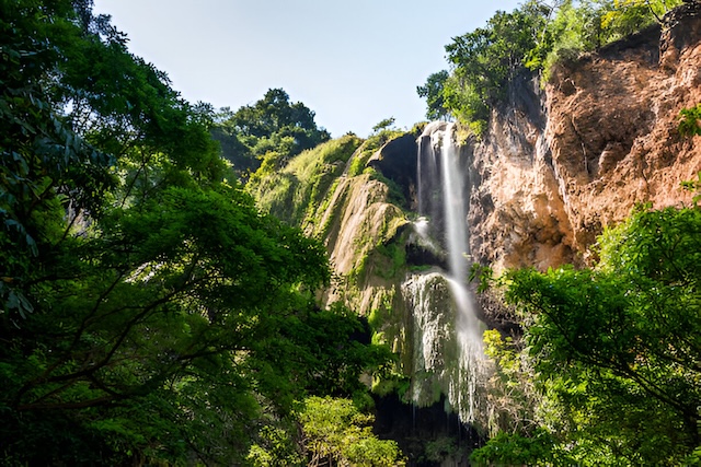 Cascade tombant d’une falaise entourée de forêt tropicale dans le parc national d’Erawan, Kanchanaburi, Thaïlande