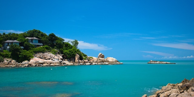 Vue côtière naturelle de Koh Samui avec villas discrètes dans la végétation, symbole de tourisme durable