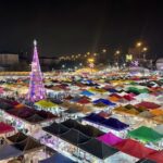 Vue aérienne d’un marché de nuit en Thaïlande, avec des dizaines de tentes colorées, une foule animée et une ambiance festive.